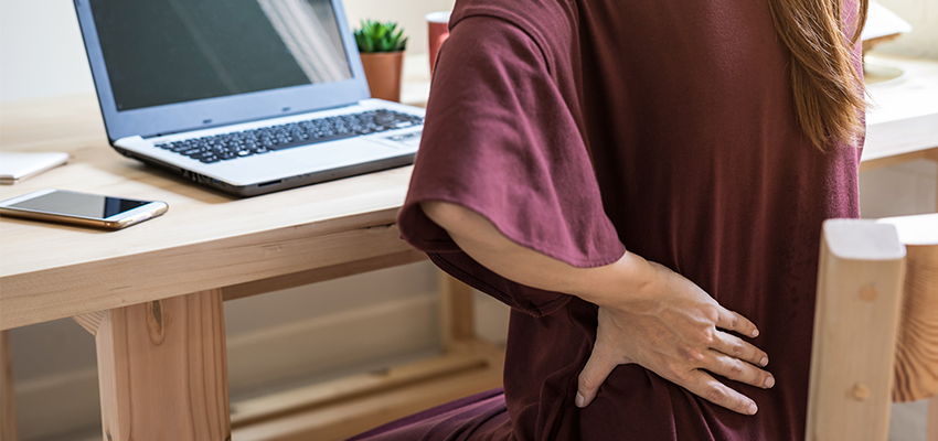 woman with lower back pain while working at desk